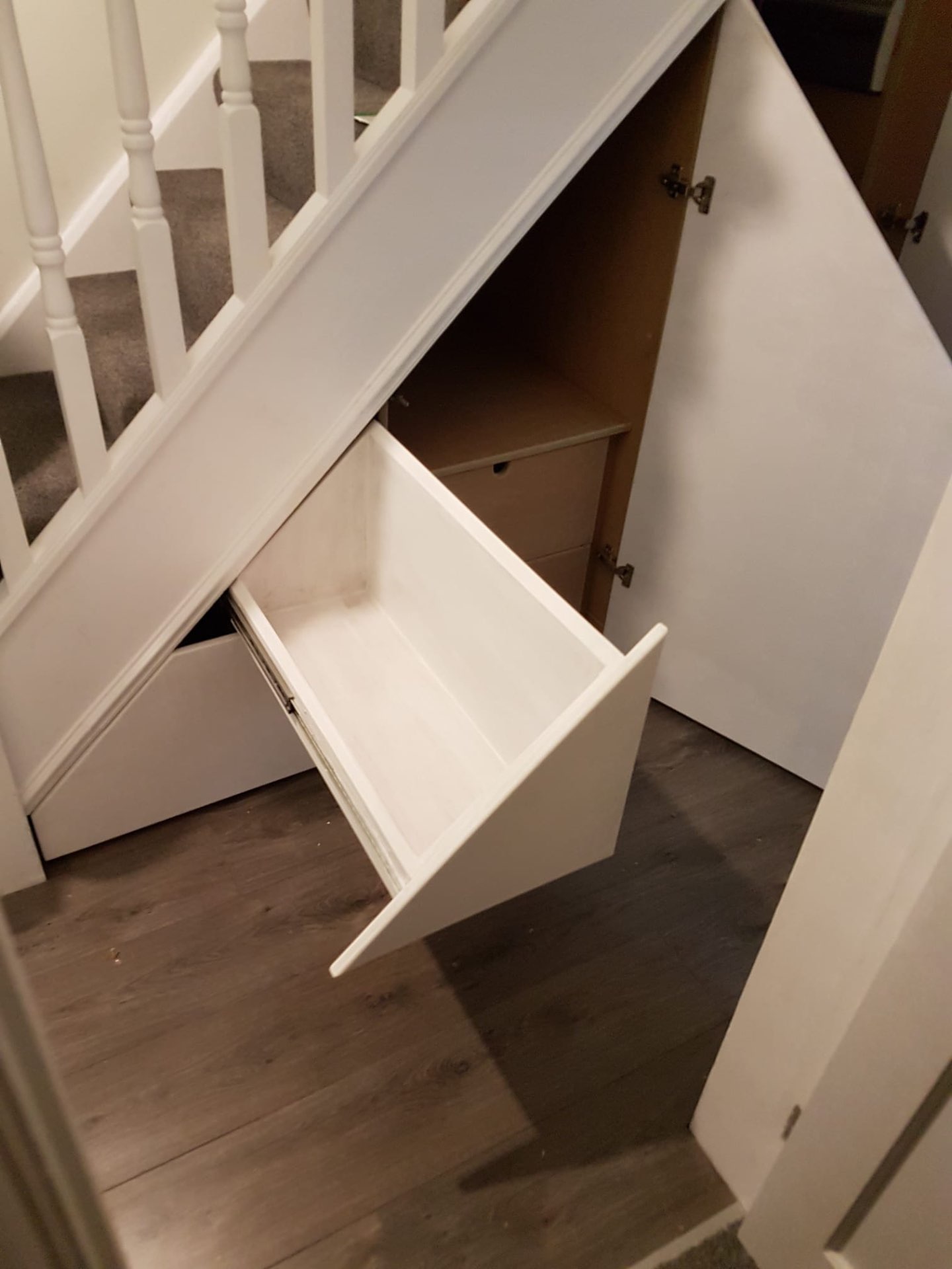 Bespoke under-stairs storage shown open with drawers and cupboards